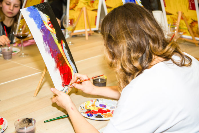 A group of Young individuals enjoying paint n sip activities outdoor. High quality photo